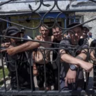 Di sebuah penjara pedesaan di Ukraina tenggara, beberapa narapidana berdiri di balik kawat berduri mendengarkan seorang petugas rekrutmen angkatan bersenjata yang menawarkan kesempatan pembebasan bersyarat kepada mereka
